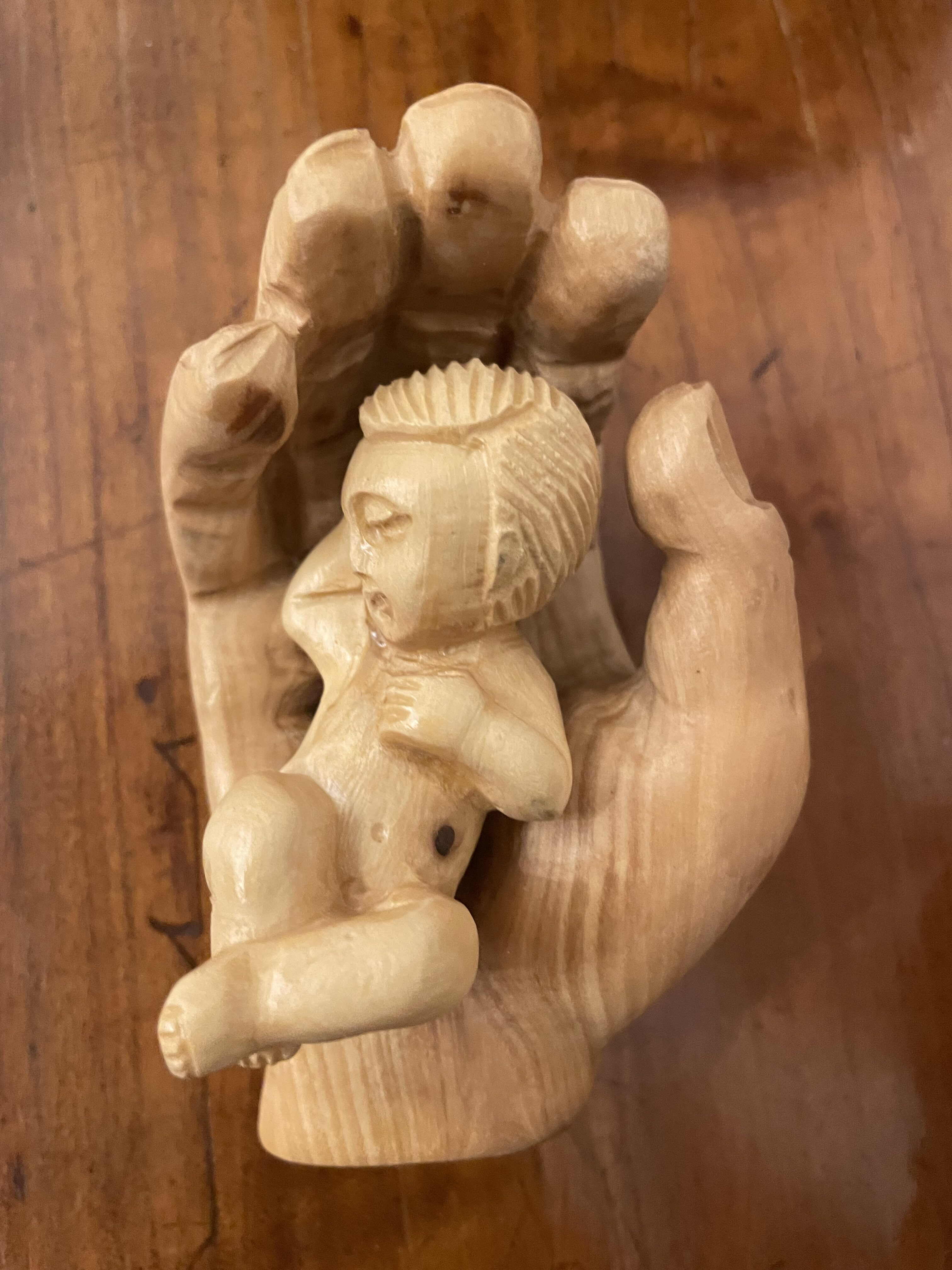 Scultura di una mano che sorregge il Bambino Gesù – simbolo di Natale e del bisogno di tornare umani – Luigi Giugno – National Daily Press