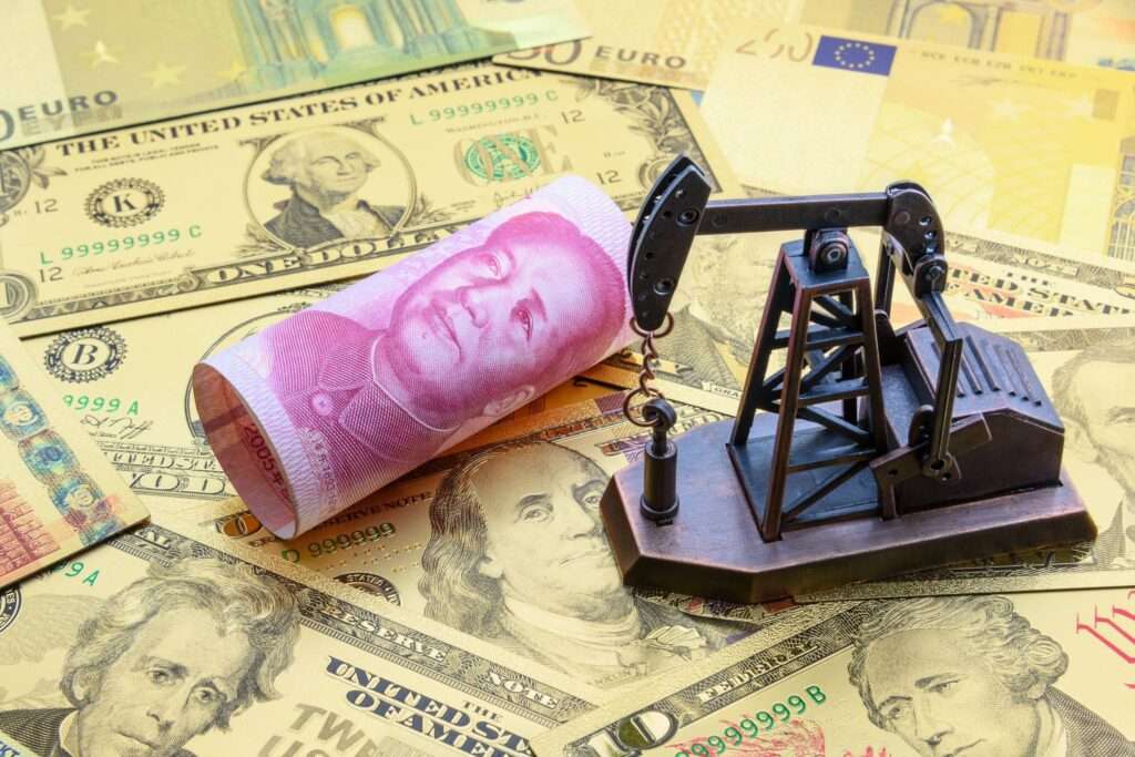 sullo sfondo ci sono dollari vari sparsi, sopra questi dllati c'è una banconota yuan arrotolata e si intravede lil volto di Mao Tze Tung stampato sulla banconota, vicino la banconota con Mao c'è una piccola trivella per petrolio 